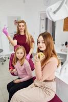 Little girl visiting dentist in clinic with her mom. Conception of stomatology. Holding apples photo