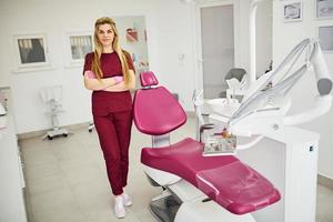 Young female dentist in uniform standing in stomatology office photo