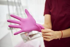 Close up view of female dentist in uniform wearing gloves in stomatology office photo