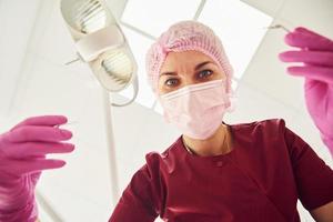 Young female dentist in protective mask working in stomatology clinic. First person view photo