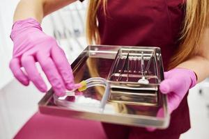 Close up view of female dentist in uniform that standing in stomatology office with tools in hands photo