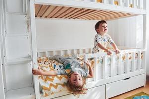 Two little boys resting and have fun indoors in the bedroom together photo