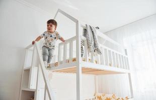 lindo niño descansando y divirtiéndose en el interior de la habitación en la cama foto