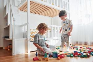 Two little boys have fun indoors in the bedroom with plastic construction set photo