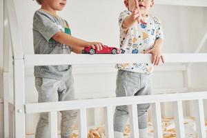 Two little boys resting and have fun indoors in the bedroom together photo