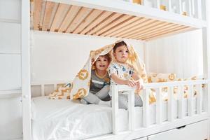 Two little boys resting and have fun indoors in the bedroom together photo