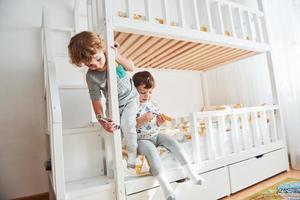 Two little boys resting and have fun indoors in the bedroom together photo