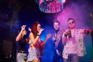 Young people is having fun in night club with colorful laser lights photo