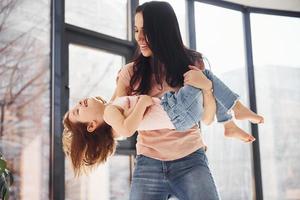 Young mother with her daughter spending weekend together on bed photo