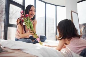 Daughter congratulates mother with holiday and gives bouquet of flowers photo