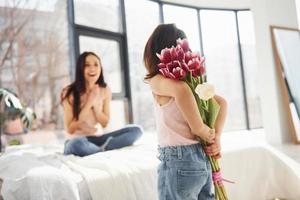 Daughter congratulates mother with holiday and gives bouquet of flowers photo