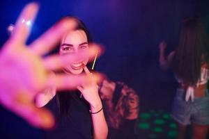 Defocused hand. Young people is having fun in night club with colorful laser lights photo