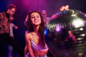 Girl sitting inside of night club with party ball in hands photo