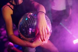Girl sitting inside of night club with party ball in hands photo