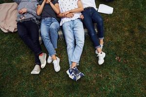 Particle view. Group of young students in casual clothes on green grass at daytime photo