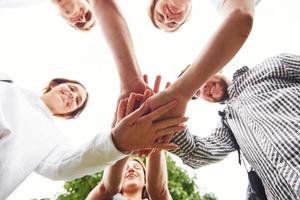 Close up view of hands of the young team of successful friends outdoors photo