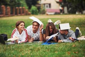 Bored and having fun. Group of young students in casual clothes on green grass at daytime photo