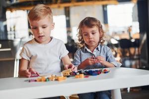 Little friends have fun with construction toys in playroom. Kindergarten educational games photo