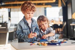 Little friends have fun with construction toys in playroom. Kindergarten educational games photo