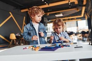 Little friends have fun with construction toys in playroom. Kindergarten educational games photo