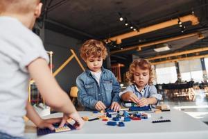 Little friends have fun with construction toys in playroom. Kindergarten educational games photo