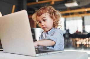 niño inteligente con ropa informal que usa una computadora portátil con fines educativos o divertidos foto
