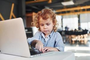 niño inteligente con ropa informal que usa una computadora portátil con fines educativos o divertidos foto