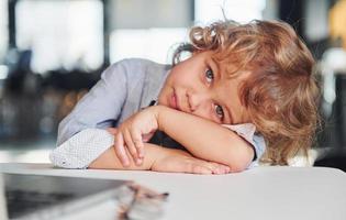 Smart child in casual clothes using laptop for education purposes or fun photo