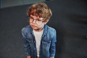 retrato de un niño lindo con gafas que está parado adentro foto