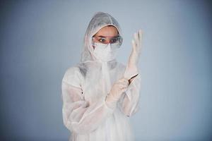 Portrait of female doctor scientist in lab coat, defensive eyewear and mask wearing gloves photo