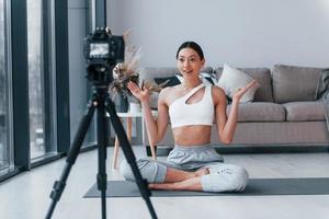 Blogger young woman with slim body shape in sportswear doing yoga indoors at home photo