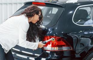 Woman with equipment cleaning modern automobile. Conception of service photo
