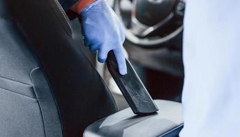 Male worker in uniform cleaning new modern car. Conception of service photo