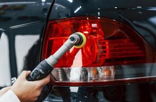 Woman with equipment cleaning modern automobile. Conception of service photo