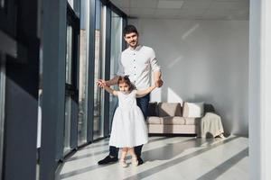 padre feliz con su hija vestida aprendiendo a bailar juntos en casa foto