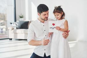 feliz Día del Padre. la hija le hace una sorpresa a papá al darle una postal con el corazón foto