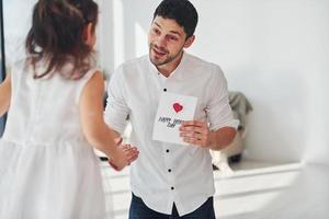 Happy father's day. Daughter makes surprise for dad by giving postcard with heart photo