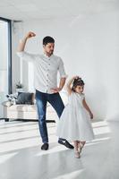 Happy father with his daughter in dress learning how to dance at home together photo
