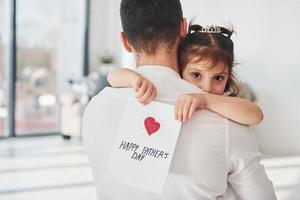 feliz Día del Padre. la hija le hace una sorpresa a papá al darle una postal con el corazón foto