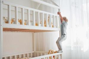 Cute little boy resting and have fun indoors in room on the bed photo