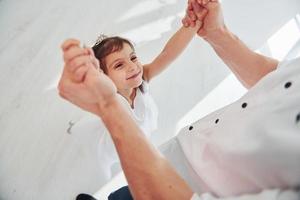 Happy father with his daughter in dress learning how to dance at home together photo