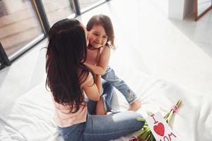 Embracing each other. Daughter congratulates mother with holiday and gives bouquet of flowers photo