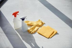 vista de cerca de las botellas de spray de limpieza con guantes en el alféizar de la ventana foto