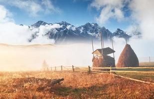 Amazing mountain landscape with fog and a haystack in autumn photo