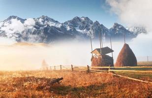 Amazing mountain landscape with fog and a haystack in autumn photo