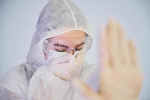 Stop the virus sign. Portrait of female doctor scientist in lab coat, defensive eyewear and mask photo