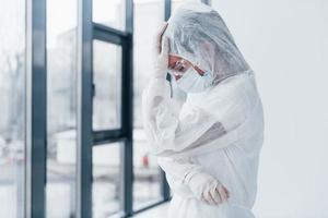 Feeling bad, tired and depressed. Portrait of female doctor scientist in lab coat, defensive eyewear and mask photo