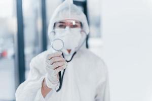 With stethoscope. Portrait of female doctor scientist in lab coat, defensive eyewear and mask photo