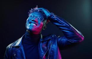 In glasses. Futuristic neon lighting. Young african american man in the studio photo