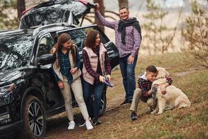 la familia feliz se divierte con su perro cerca de un camión moderno al aire libre en el bosque foto